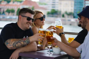 Friends enjoying beers on board a private Budapest river cruise, relaxed daytime atmosphere with city views
