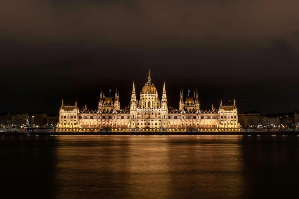Budapest Parliament lit up at night, reflected on the Danube.
