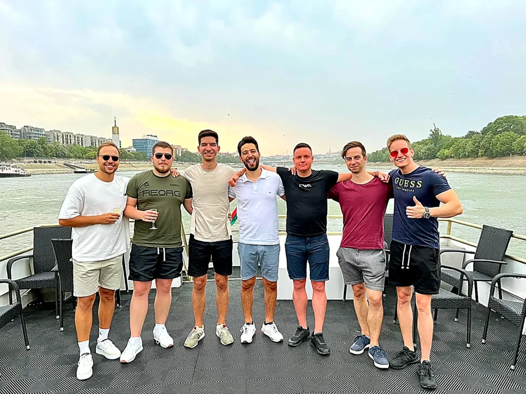 Group of friends posing on the open deck during a private boat cruise on the Danube in Budapest at sunset, a social proof photo for celebration and stag cruises.