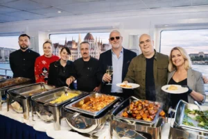 Dinner cruise buffet on a boat in Budapest with the catering team and guests, hot dishes served with Danube views in the background.