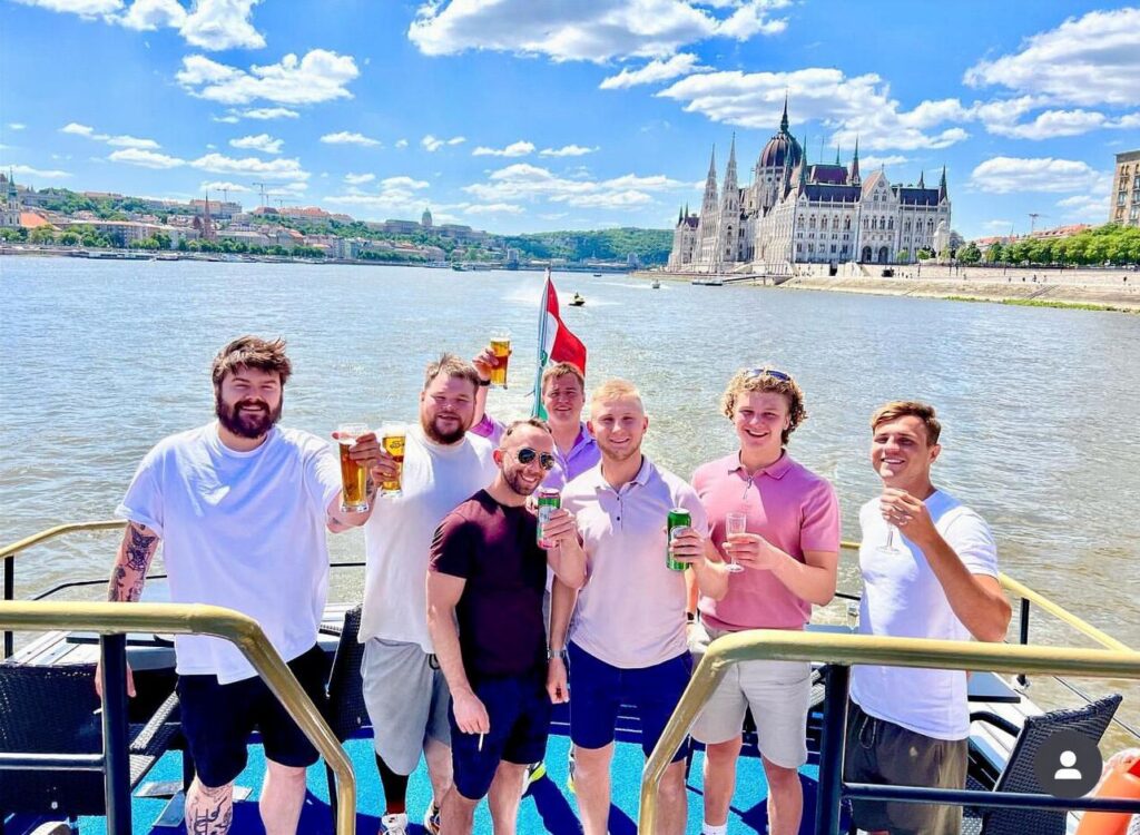 Budapest stag group celebrating on a private party boat with drinks, music, and Danube river views.