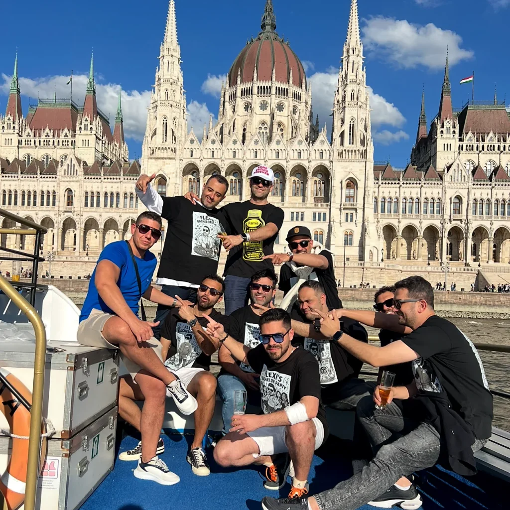 Stag group relaxing on a private boat on the Danube in Budapest, with the Hungarian Parliament building in the background on a sunny day.